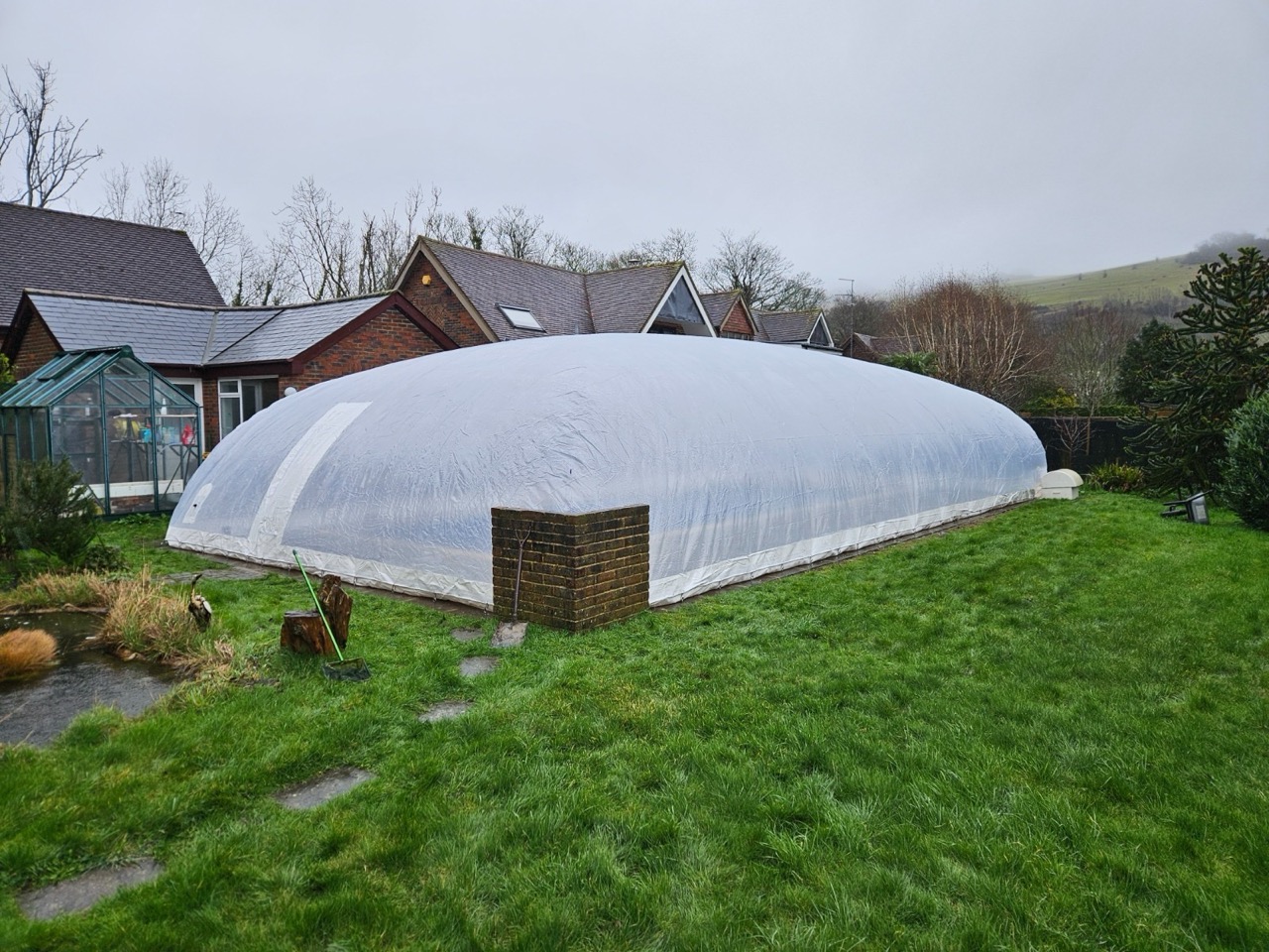 Inflatable pool dome installed in a UK backyard, covering a swimming pool for year-round use and protection from the weather.